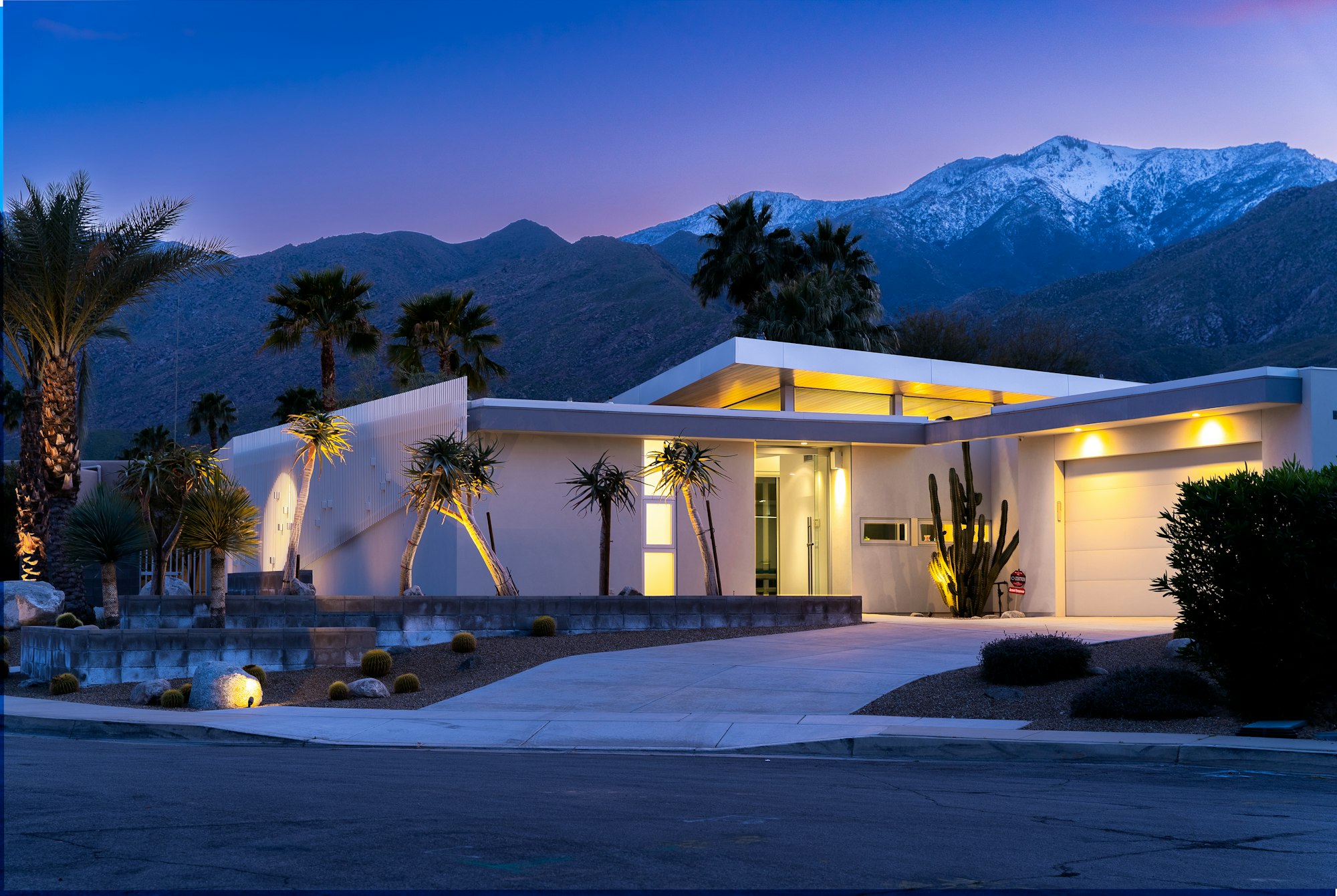 White Arizona home framed by palm trees with a mountain ridge behind it